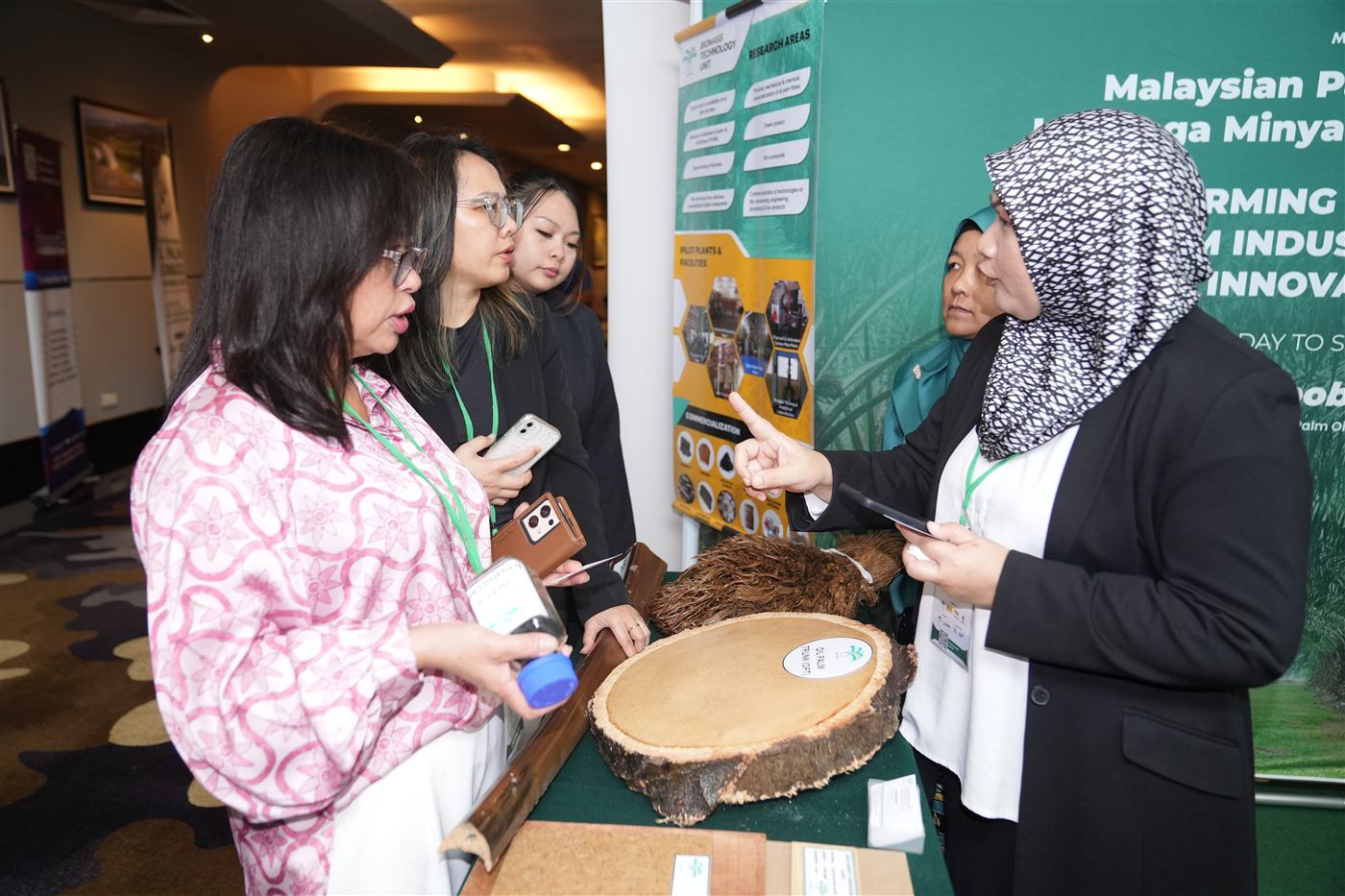 Delegates examining oil palm biomass material samples at an exhibition booth
